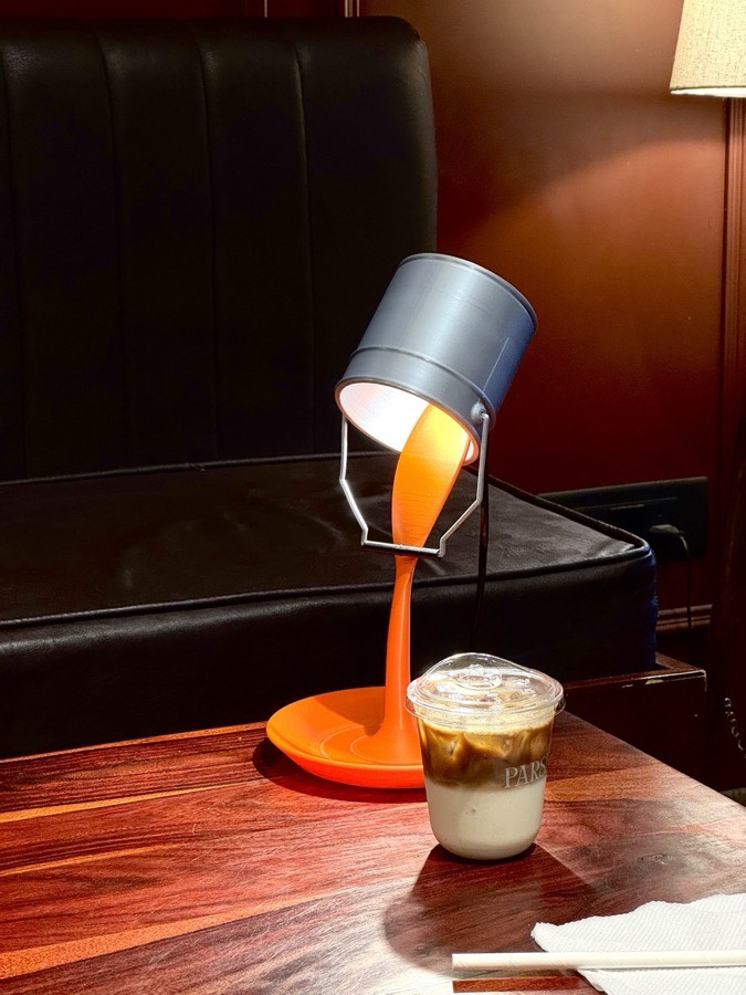 Spill lamp glowing warmly on a wooden café table beside an iced coffee